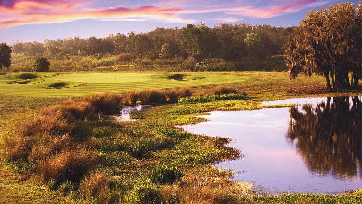 ChampionsGate International course at golden hour with water, fairway, bunkers, and resort skyline.